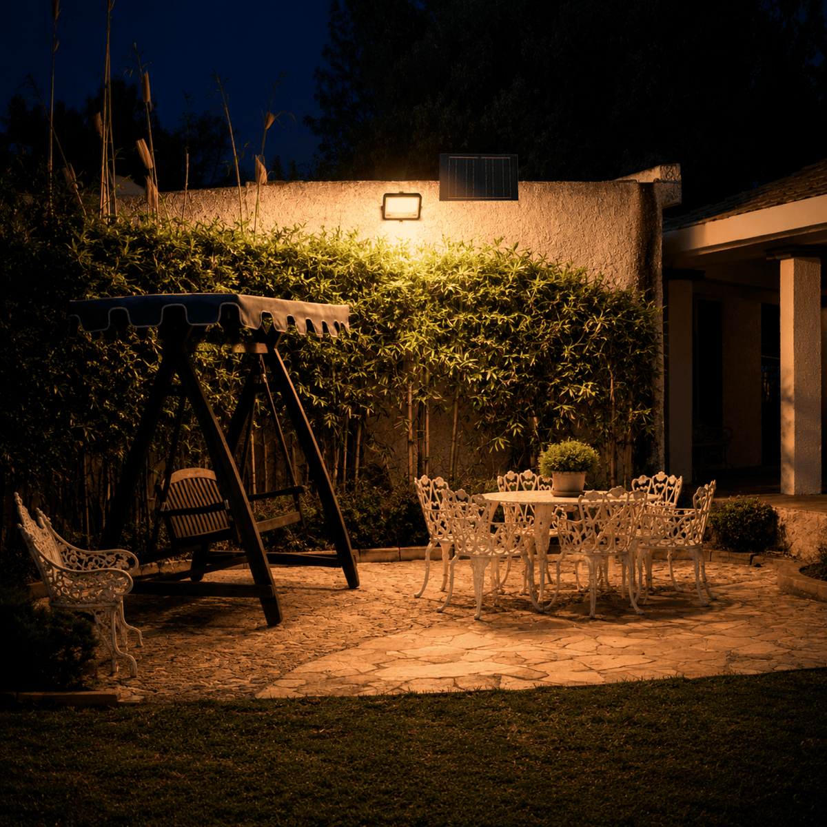 Proyector Solar LED EcoLuz Plus 100W iluminando el patio de una casa durante la noche con energía solar.