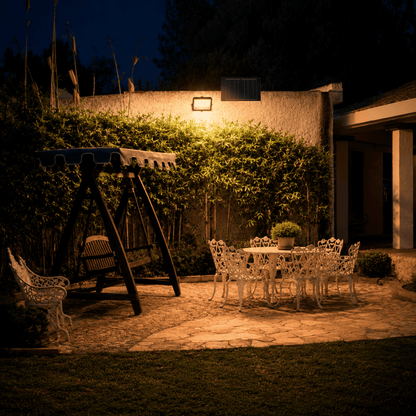 Proyector Solar LED EcoLuz Plus 100W iluminando el patio de una casa durante la noche con energía solar.