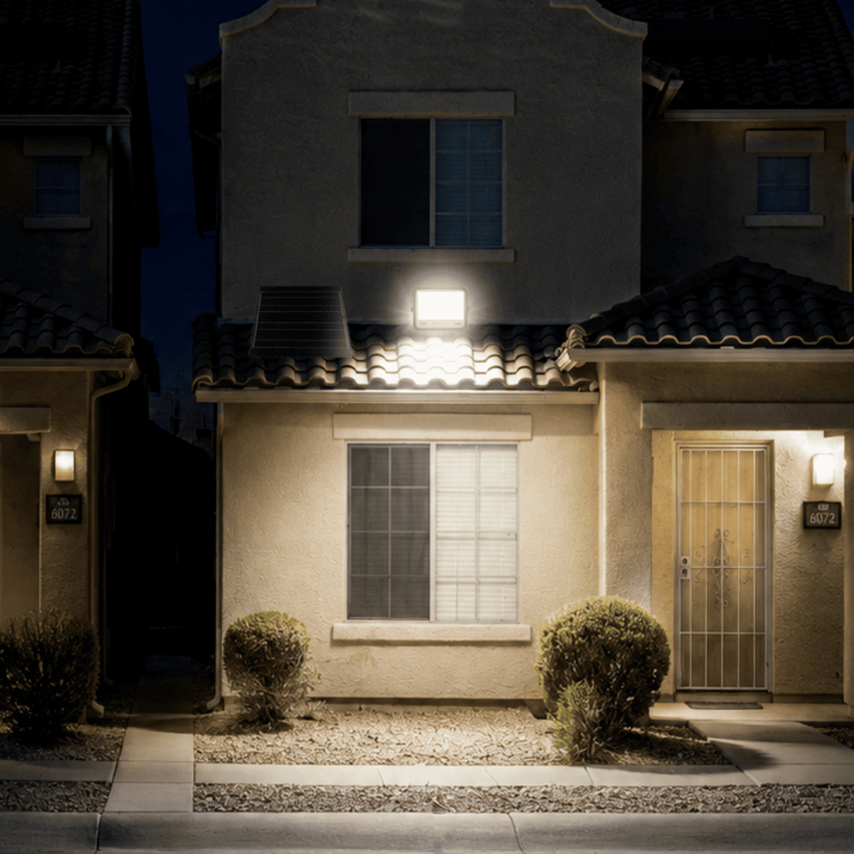 Proyector Solar LED EcoLuz Plus 150W iluminando el frontis de una vivienda con luz LED alimentada por energía solar.